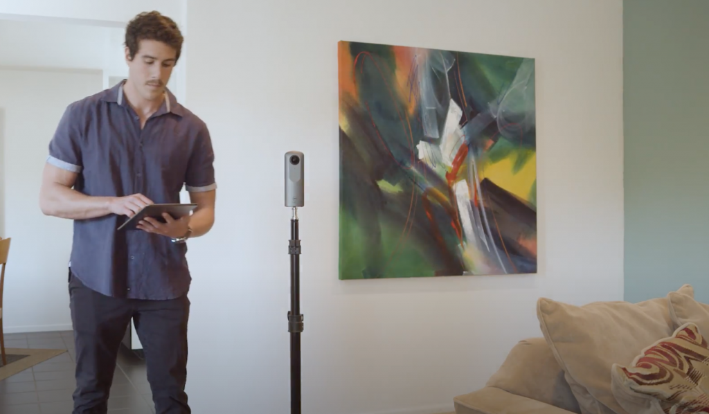 Man taking 360 degree pictures of a living room.